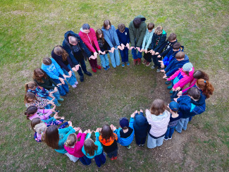 Kinder bilden einen Kreis auf einer Wiese